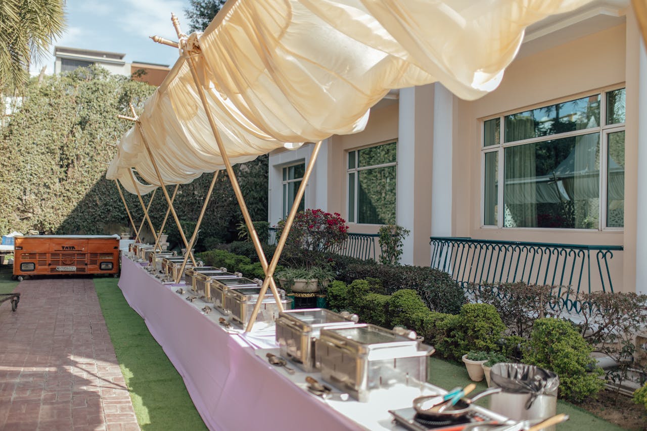 Services Elegant outdoor buffet setup with chafing dishes and canopy. Perfect setting for a garden party or wedding reception.